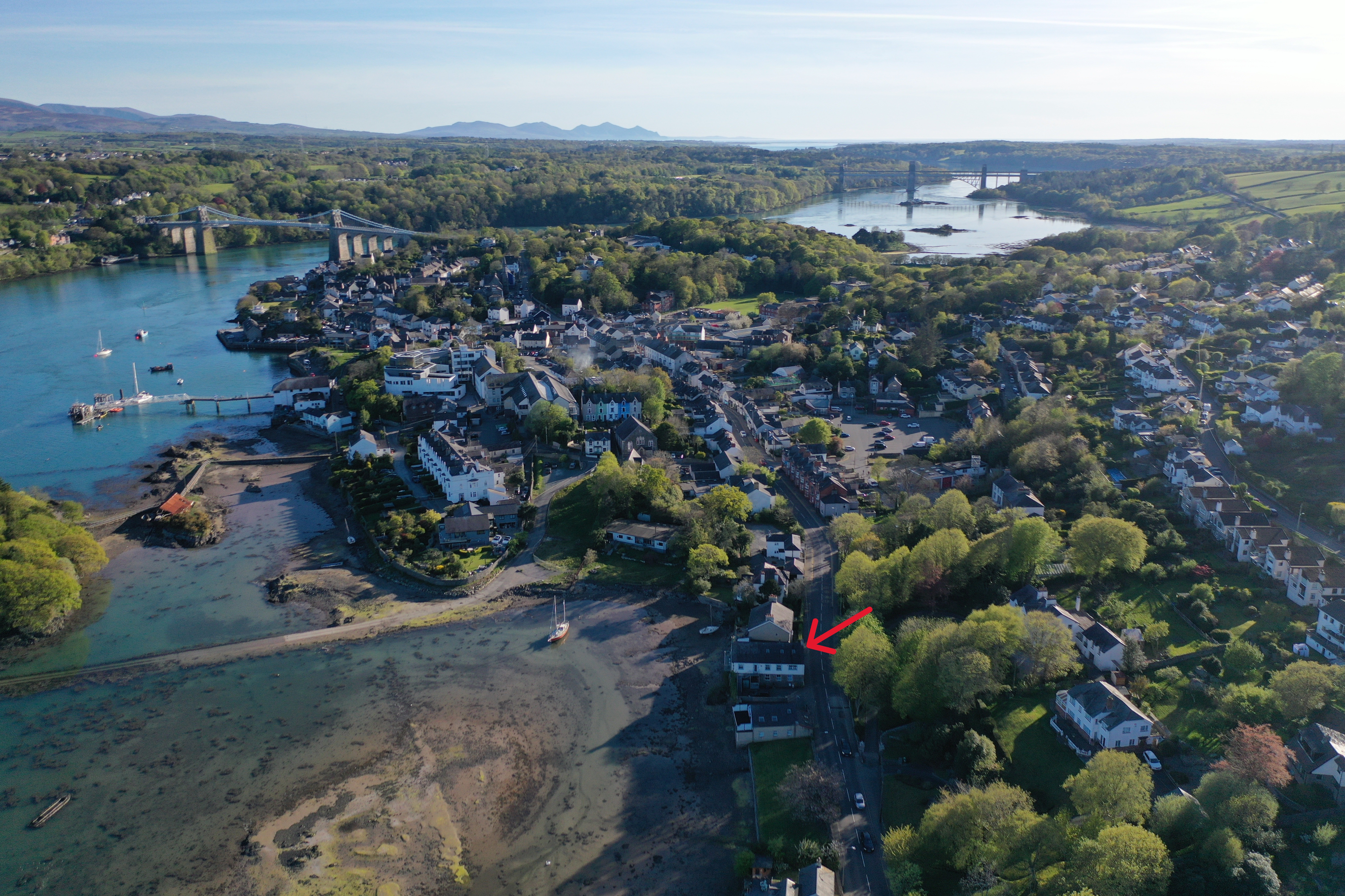 Aerial view of Menai Bridge town and The Old Mill location marked with red arrow